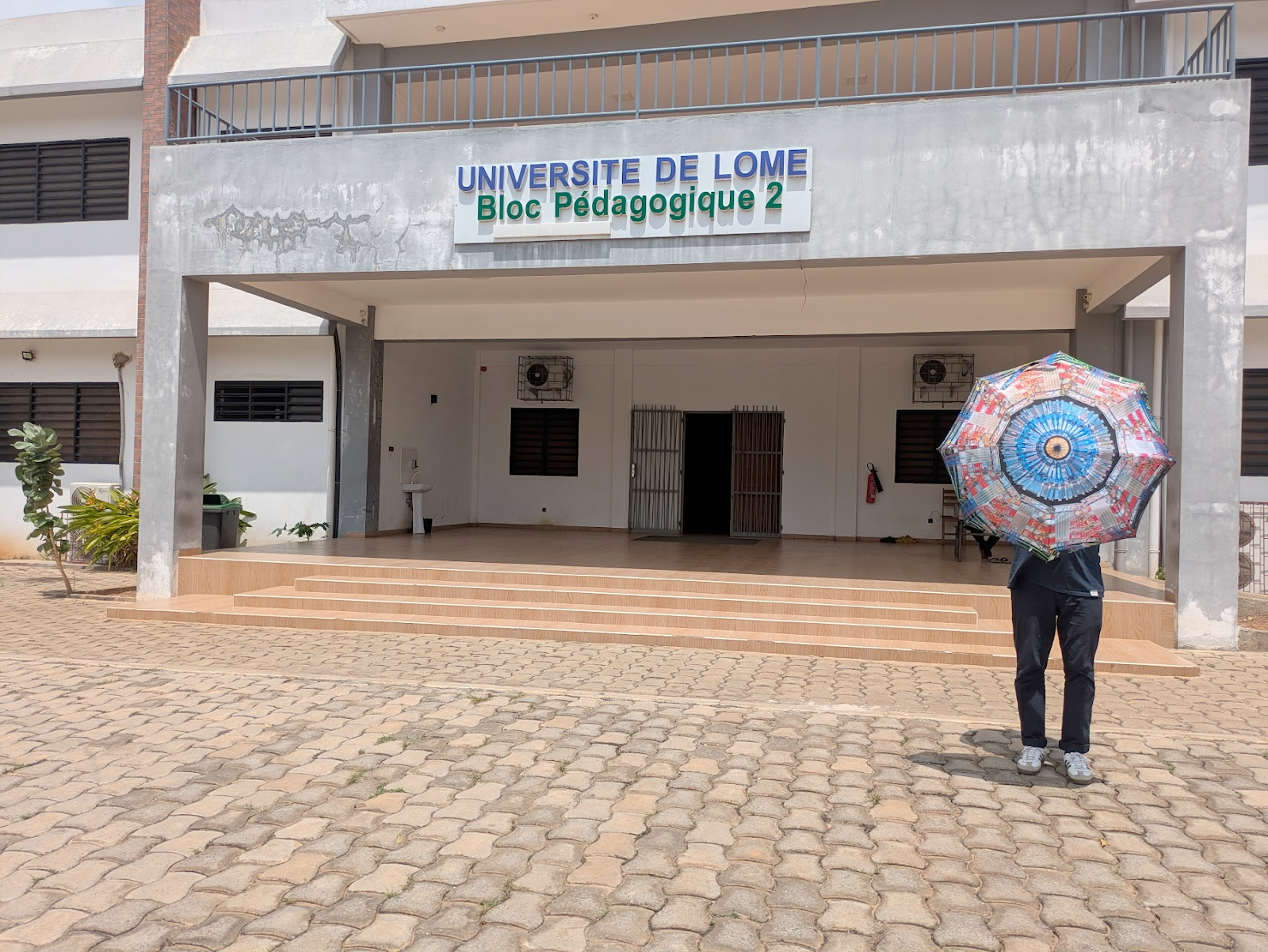 The author behind the CMS umbrella outside Bloc Pedagogique 2 at the University of Lome, where the LHC Open Data Workshop took place.
